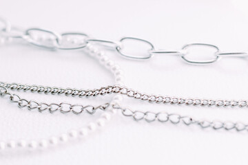 A necklace of white beads with chains of jewelry on a white aesthetic background.