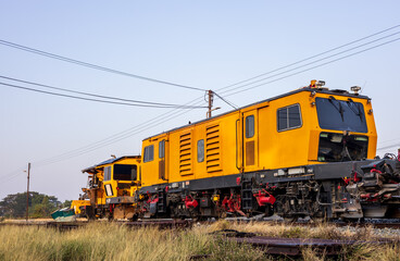 Fototapeta na wymiar Low angle view of yellow train stationary on grassy track near station.