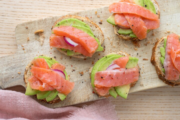 Toasts with avocado and smoked salmon on the wooden board