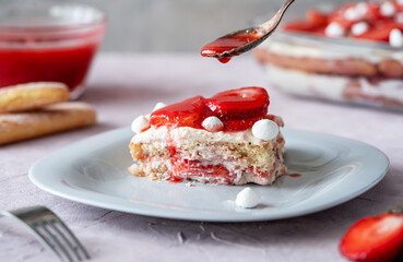 Italian traditional dessert tiramisu with strawberries. One piece of cake on a plate closeup,...