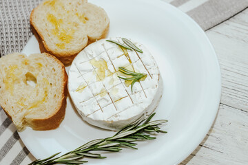 White baguette cut into pieces with olive oil and Camembert cheese on the table.