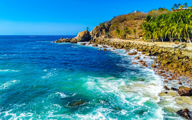 Surfer waves turquoise blue water rocks cliffs boulders Puerto Escondido.