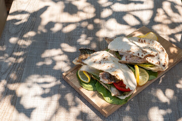 sandwich balik Ekmek with grilled fillet of mackerel, tomatoes, onions and lettuce in pita bread...