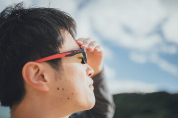 視覚障害者の男性が眩しそうに沖縄の空を眺めている