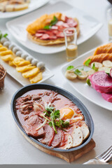 Stewed meat with fried eggs in saucepan on breakfast table