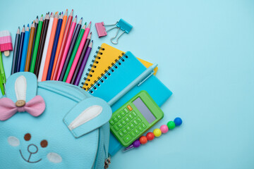 Opened School backpack with stationery on blue background. Organization of the school space. Concept back to school. School supplies.
