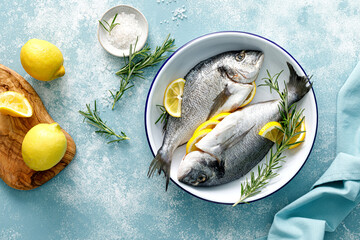 Fresh raw dorado fish cooking with lemon and rosemary. Sea bream, dorado. Seafood, healthy food. Top view - 604935131