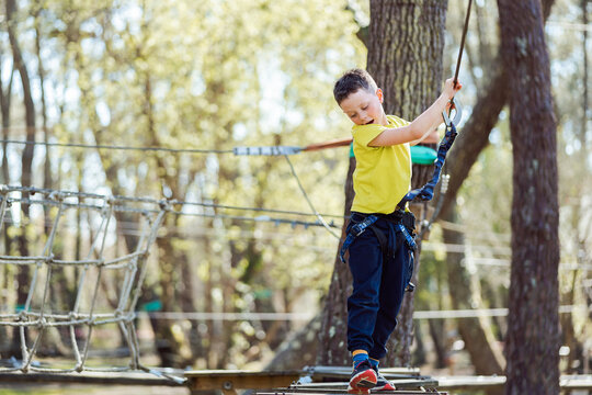 Happy boy standing on rope bridge in park