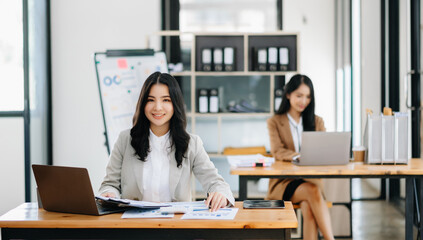 Young attractive Asian female office worker business suits smiling at camera in modern office .