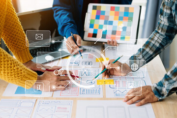  UX developer and ui designer brainstorming about mobile app interface wireframe design with customer breif and color code at office. with virtual icon.
