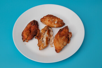 Fried fish in a white plate on blue background.
