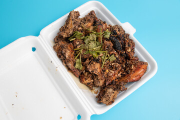 Stir Fried Chicken with Black Pepper in foam box on blue background.