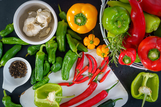 a colorful assortment of peppers, hot peppers and chili, decorated with various assesoires on a wooden table.
