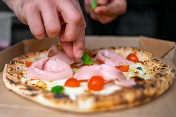 Obraz na płótnie Canvas man chef hand cooking napolitana pizza with mortadella and cheese 