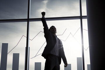 Business Success: An unrecognizable man celebrating with raised arms in front of a growth chart