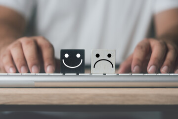 Wood block face sad and wood block smiles on keyboard for evaluation. Customer satisfaction or emotional evaluation concept. Positive and negative emotions. Mental health, wellness and healthy concept