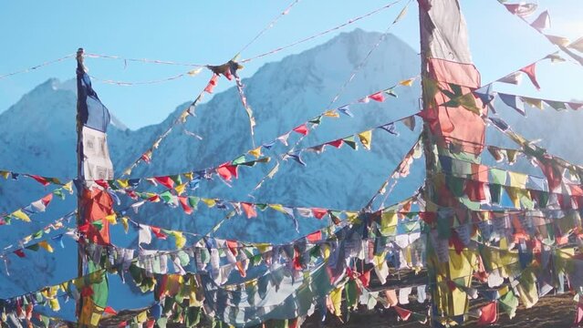 Slow motion shot of prayer flags waving in the wind in front of the snow covered Himalayan mountains at Kunzum Pass on the way to Kaza from Manali in Himachal Pradesh, India. Prayer flags at Kunzum. 