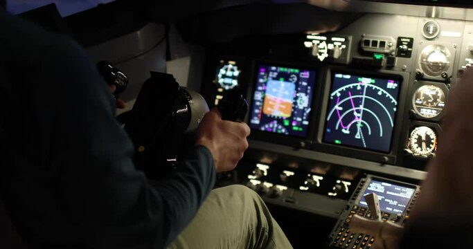 Close-up of the pilot's hands holding the helm of an aircraft. Illuminated aircraft control panel. Flight control concept. Airplane flight simulation.