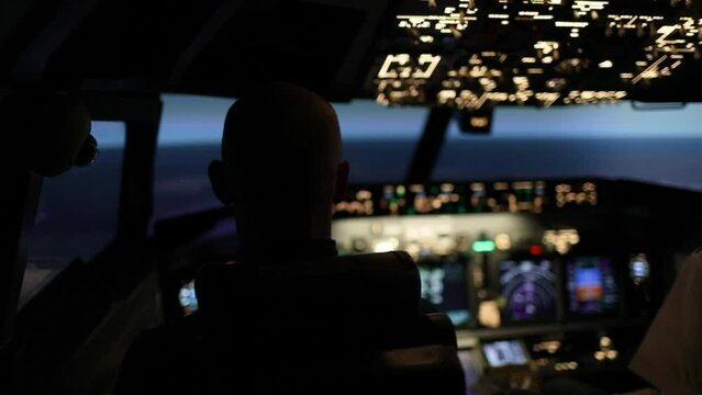 Airplane flight simulation. Two pilots are in the cockpit. Aircraft control. Twilight. Close-up of the illuminated dashboard plane. Airplane flight simulation. Airplane flight concept.