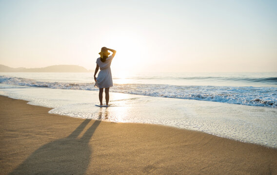 Young asian woman relaxing on the beach at sunrise. - Powered by Adobe