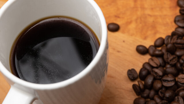 Black Coffee with Coffee Beans on the side on a Wood Board