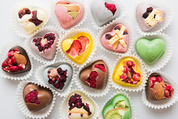 chocolate sweets in the form of a heart with fruits and nuts on a colored background. top view with space for text, holiday concept