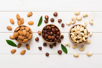 Assortment of nuts in wooden bowl on colored table. Cashew, hazelnuts, walnuts, almonds. Mix of nuts Top view with copy space