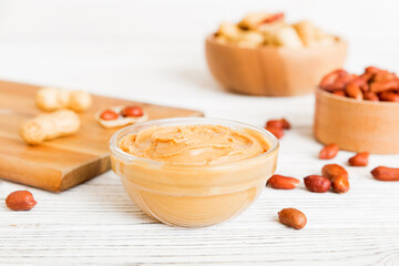 Bowl of peanut butter and peanuts on table background. top view with copy space. Creamy peanut pasta in small bowl