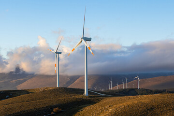 4k Time lapse of turbines of a wind farm in the Italian mountains in a romantic and cloudy sunset....