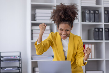 Excited african american woman sit at desk feel euphoric win online lottery, happy black woman...