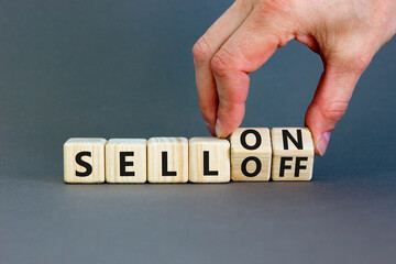 Sell on or off symbol. Businessman turns wooden cubes and changes word Sell off to Sell on. Beautiful grey table grey background. Business and sell on or off concept. Copy space.