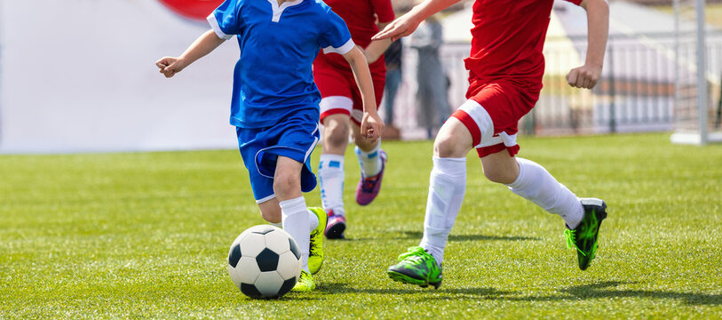 Soccer Players in a Duel. Elementary Age Kids in Soccer Clubs of Soccer Academies. Two Children Sports Team Kicking Football Match on Grass Pitch