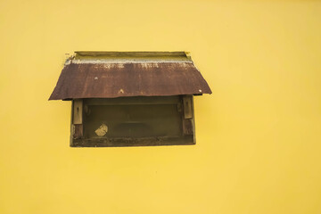 Photo of old glass ventilation window with canopy on yellow walls. With empty blank text copy space.