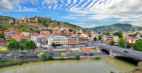 Panorama of the old town of the capital of Georgia, the city of Tbilisi in summer sunny day. Kura river, Metekhi bridge, ancient Narikala fortress and colorful old buildings in Tbilisi, Georgia © Artur