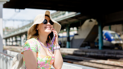 Happy tourist at the train station using your smart phone, summer vacation concept