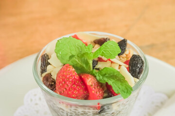 Close-up top view photo fruit pudding with various toppings such as mint leaves, strawberries, raisins, sliced ​​almonds and chia seeds. Concept for healthy eating, fat loss, organic food, vegan diet.