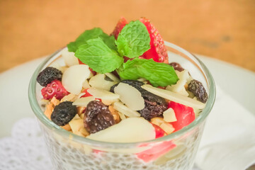 Close-up top view photo fruit pudding with various toppings such as mint leaves, strawberries, raisins, sliced ​​almonds and chia seeds. Concept for healthy eating, fat loss, organic food, vegan diet.