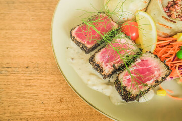 Three pieces of seared tuna with salad wrapped and quinoa on wooden table. Concept for healthy food, fat loss, weight loss, diet menu, vegetarian vegan, whole organic food, omega-3, dietary fiber.
