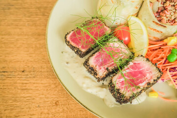 Three pieces of seared tuna with salad wrapped and quinoa on wooden table. Concept for healthy food, fat loss, weight loss, diet menu, vegetarian vegan, whole organic food, omega-3, dietary fiber.