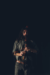 Fototapeta premium Bagpipe player playing his instrument in an auditorium with stage lights and a black background.