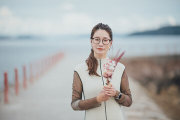 海でドライフラワーを持っている表皮水疱症の女性