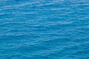 Aguas azules profundas en un día soleado de verano. Superficie ondulada de agua de mar observada desde la parte superior de Ciolo de Gagliano del Capo, Puglia, Italia. - obrazy, fototapety, plakaty