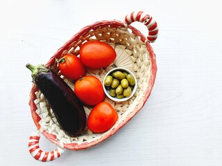 basket with fresh ingredients mediterranean eggplant, tomatoes, olives and white background