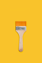 Un pincel de pintura con asa de madera sobre un fondo amarillo brillante liso y aislado. Vista superior y de cerca. Copy space. Formato vertical