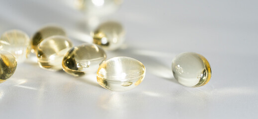 Fish Oil Omega 3 on white background, vitamin D yellow supplement gel capsules, macro shot	
