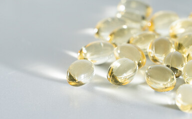 Fish Oil Omega 3 on white background, vitamin D yellow supplement gel capsules, macro shot	

