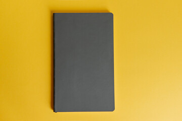 book on yellow background. gray notebook on a bright background. business composition, training, freelance.