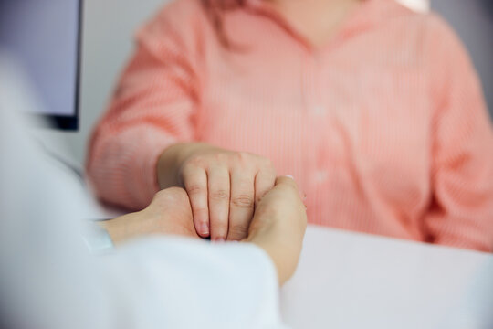 Close-up of a caring female doctor's hands, reassuring her female patient.
