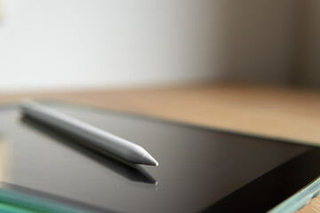 tablet and pencil close-up with blurred background.