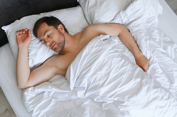 Obraz na płótnie Canvas Handsome man sleeping under soft blanket in bed at home